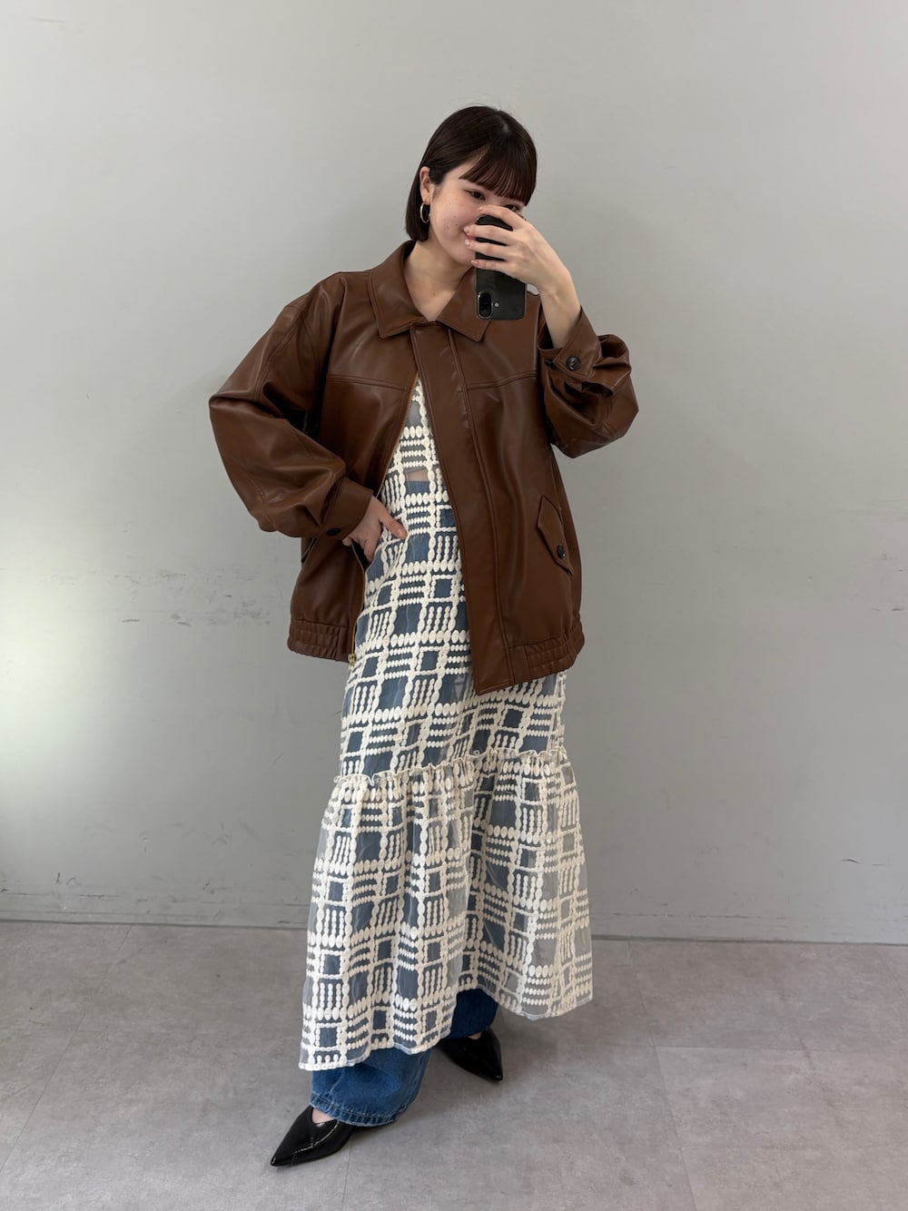 ブラウン系のブルゾン、ホワイト系のワンピース、ブルー系のデニムパンツを着用したレディースの秋コーディネートの1枚目の写真