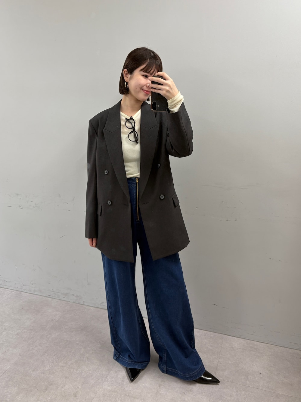 グレー系のテーラードジャケット、イエロー系のTシャツ/カットソー、ブルー系のデニムパンツを着用したレディースの秋コーディネートの1枚目の写真