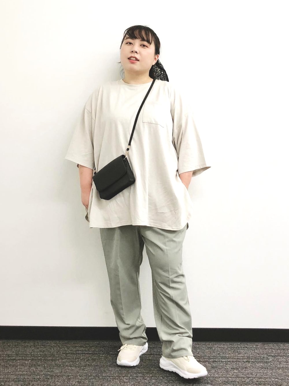 グリーン系のパンツ、ホワイト系のトップス、ブラック系のバッグを着用したレディースの秋コーディネートの1枚目の写真