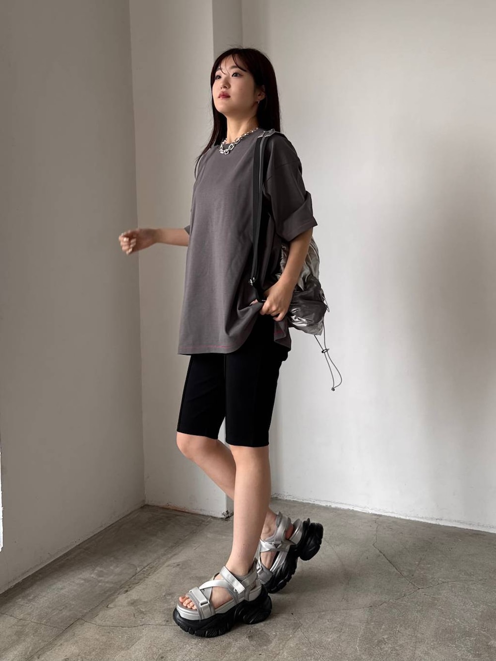 グレー系のサンダル、シルバー系のバックパック/リュック、グレー系のTシャツ/カットソーを着用したレディースの春コーディネートの1枚目の写真