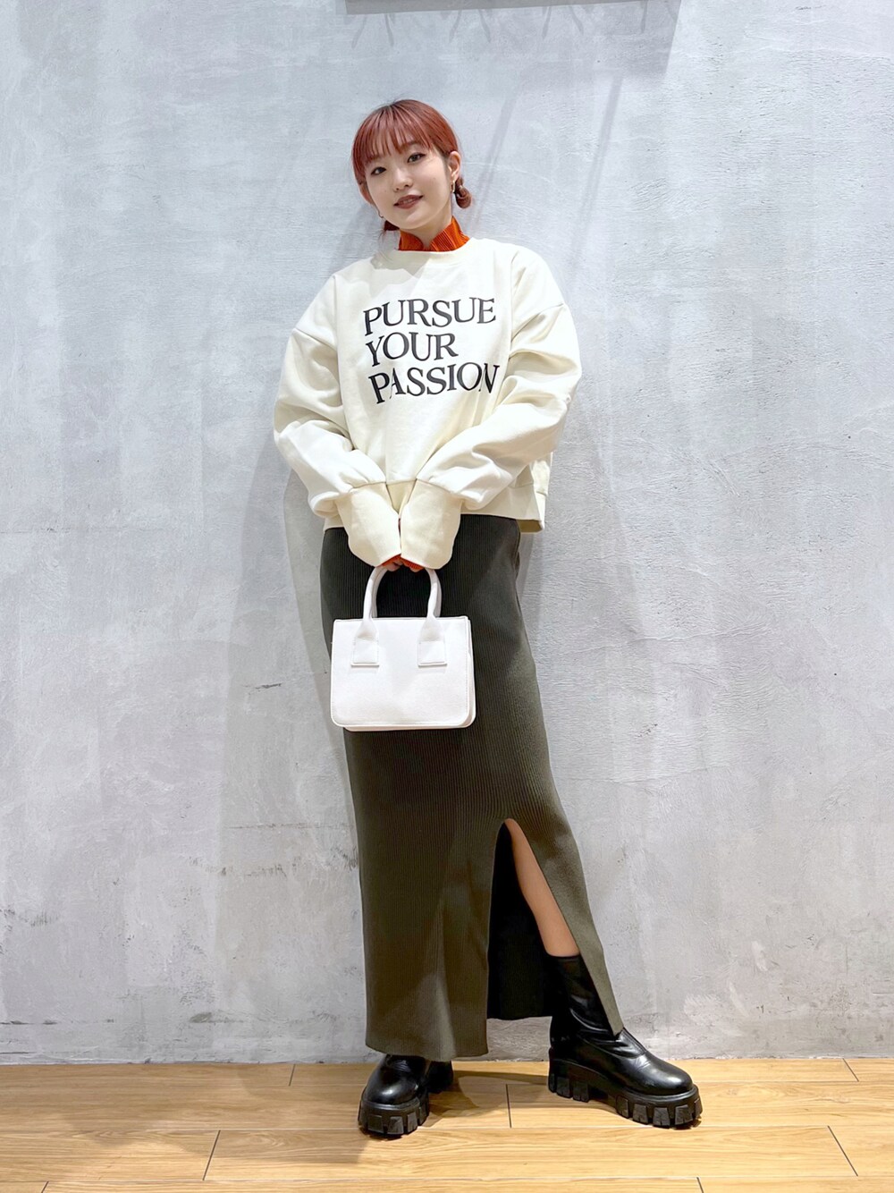 ホワイト系のショルダーバッグ、ベージュ系のスウェット、グリーン系のスカートを着用したレディースの冬コーディネートの1枚目の写真