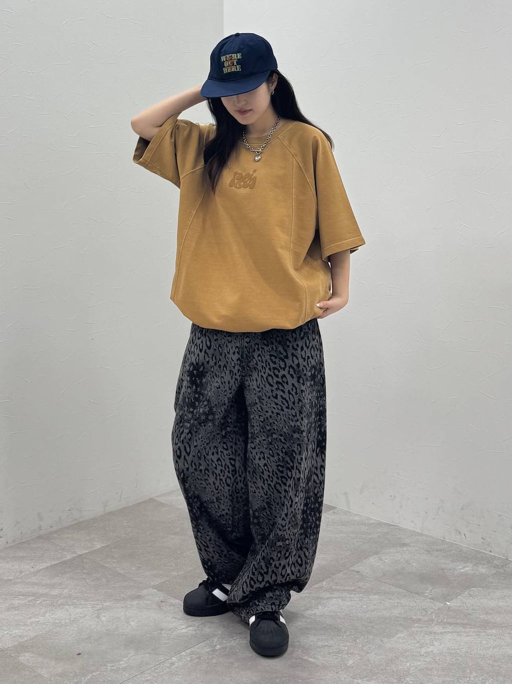 ブラック系のデニムパンツ、イエロー系のTシャツ/カットソー、ブルー系のキャップを着用したレディースの春コーディネートの1枚目の写真