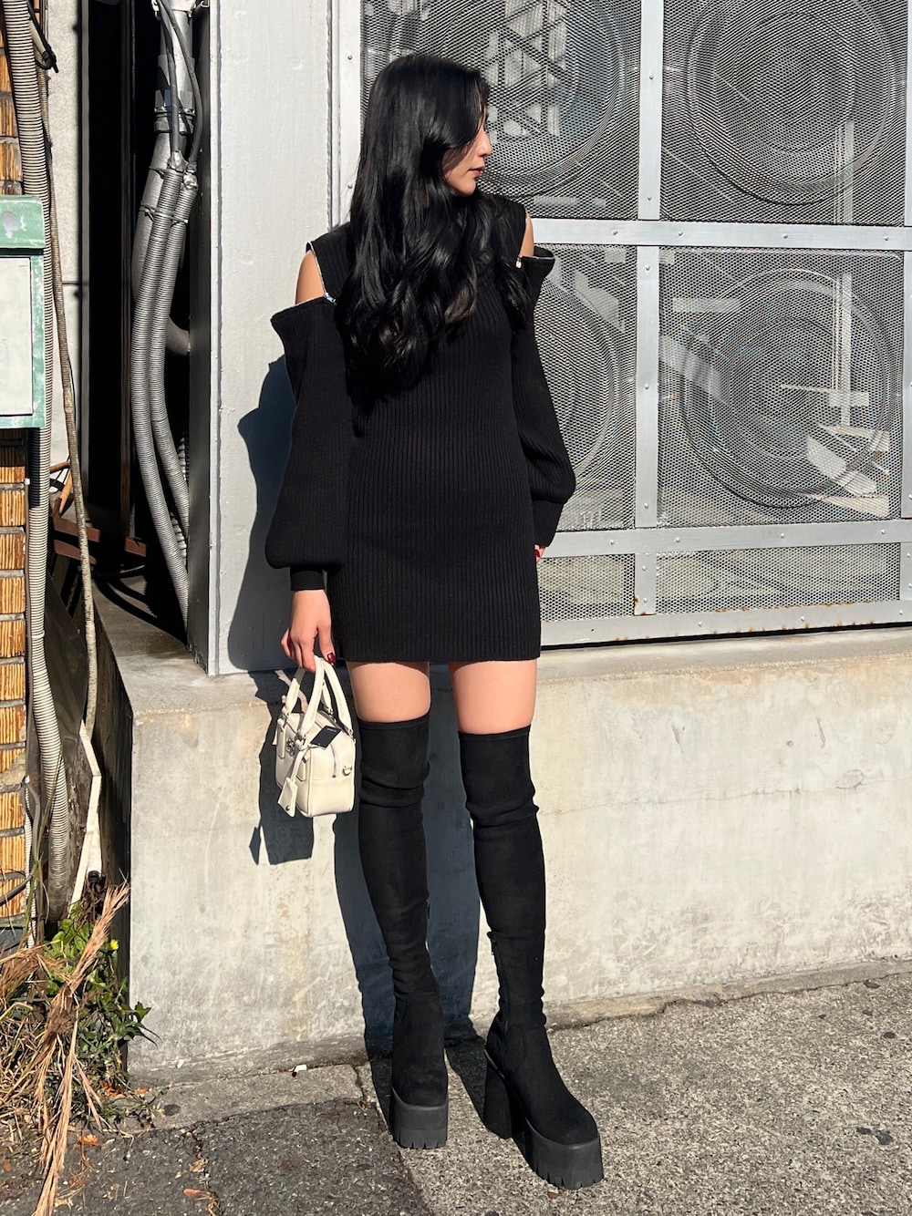 ブラック系のワンピース、ホワイト系のハンドバッグ、ブラック系のブーツを着用したレディースの冬コーディネートの1枚目の写真