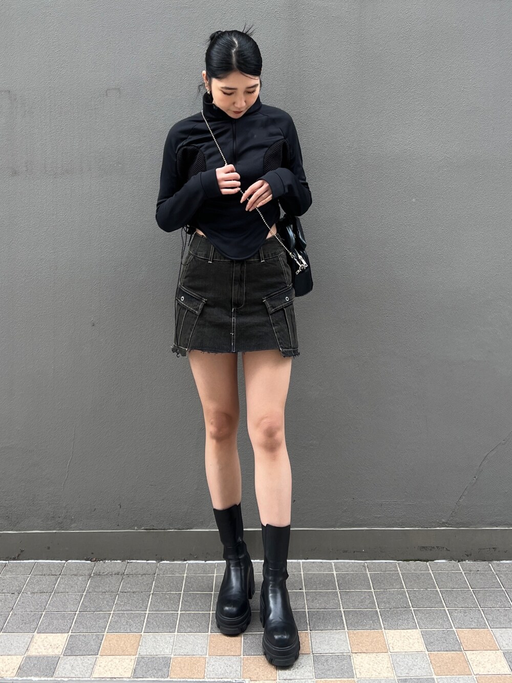 ブラック系のスカート、ブラック系のブーツ、ブラック系のハンドバッグを着用したレディースの春コーディネートの1枚目の写真