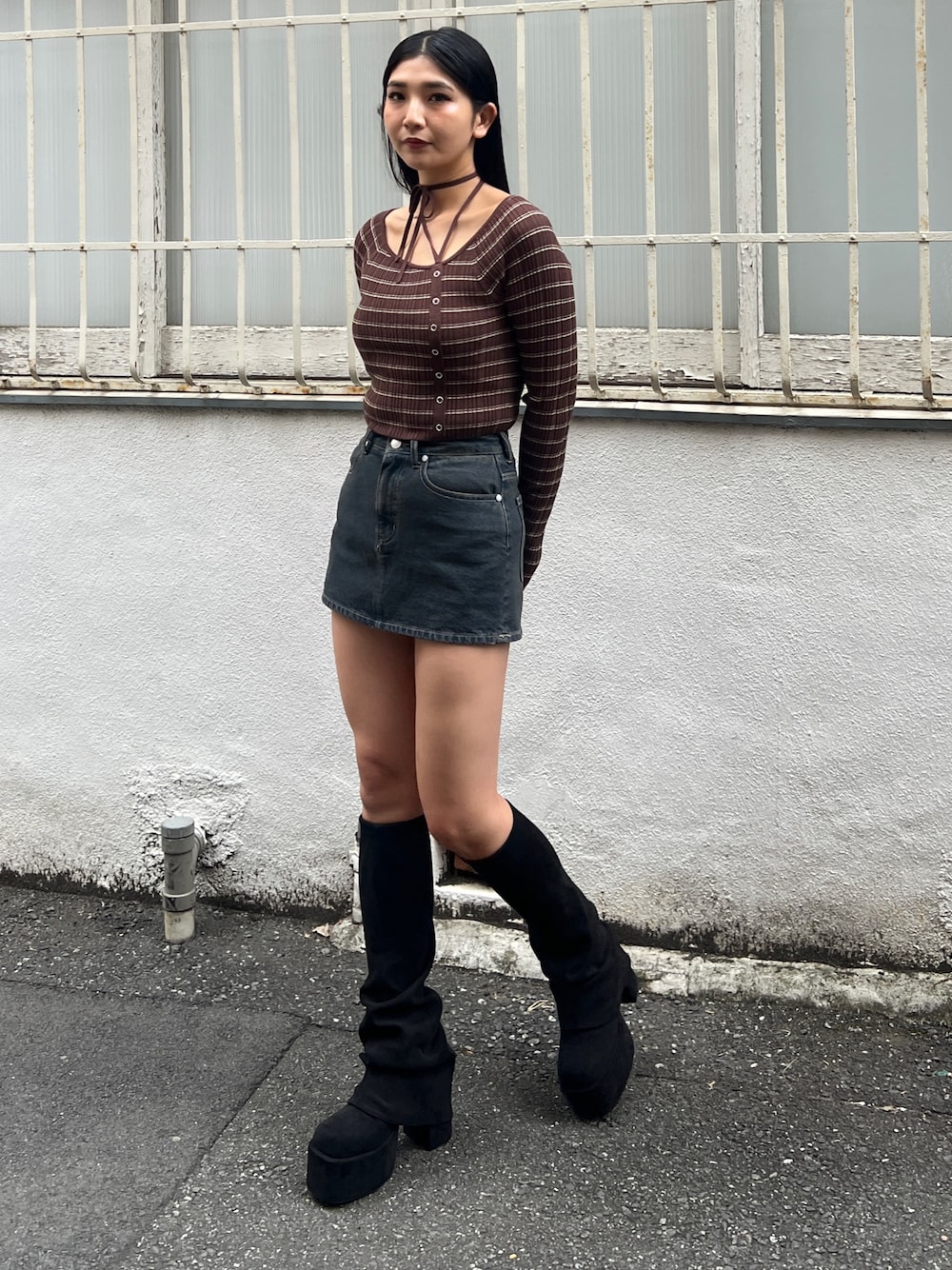 ブラウン系のニット/セーター、ブルー系のスカート、ブラック系のブーツを着用したレディースの冬コーディネートの1枚目の写真