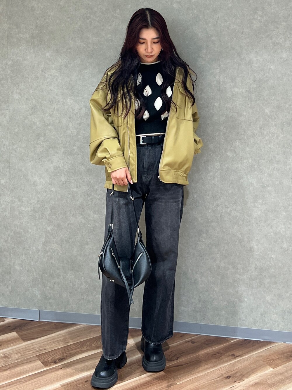 イエロー系のブルゾン、ブラック系のニット/セーター、ブラック系のデニムパンツを着用したレディースの冬コーディネートの1枚目の写真