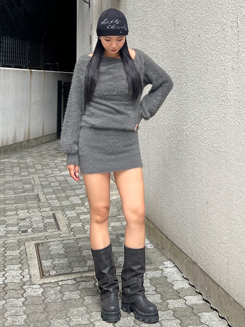 グレー系のワンピース、ブラック系のブーツ、ブラック系のニットキャップ/ビーニーを着用したレディースの冬コーディネートの1枚目の写真