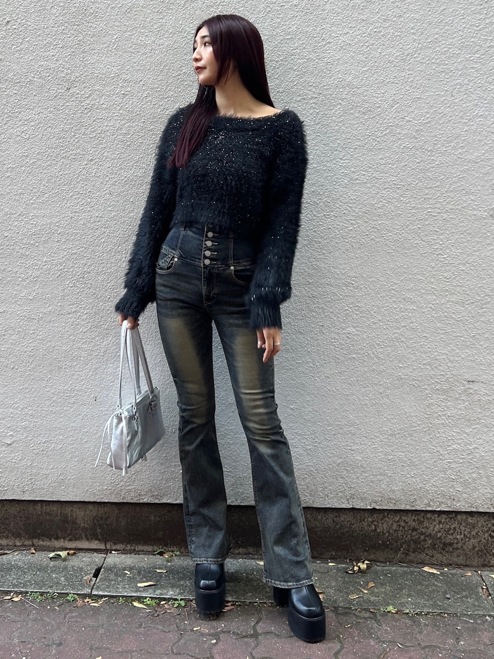 ブラック系のニット/セーター、ブルー系のデニムパンツ、ブラック系のブーツを着用したレディースの秋コーディネートの1枚目の写真