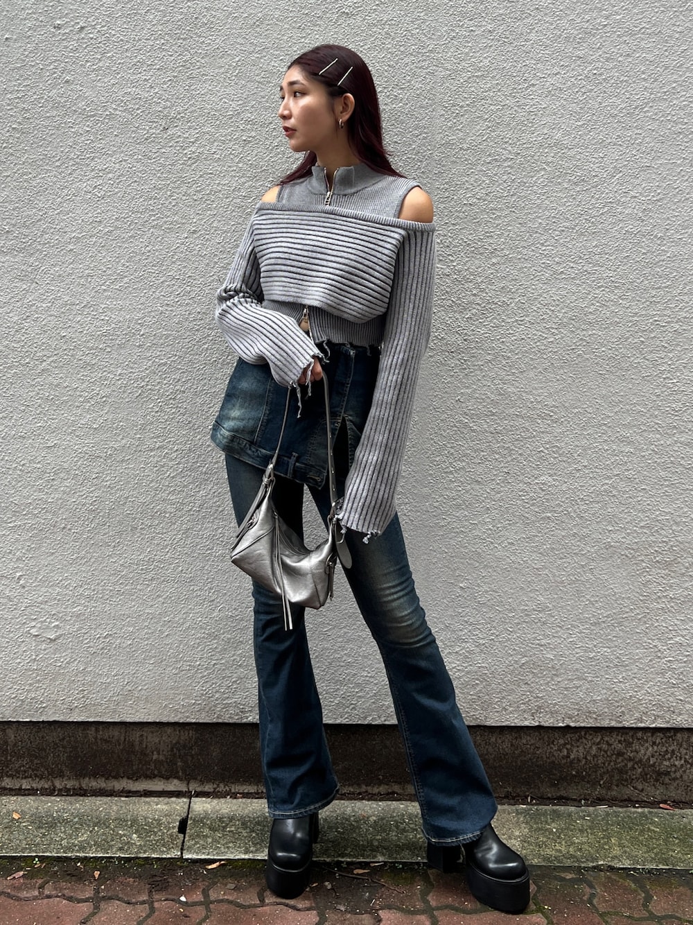 グレー系のニット/セーター、ブルー系のデニムパンツ、シルバー系のハンドバッグを着用したレディースの秋コーディネートの1枚目の写真
