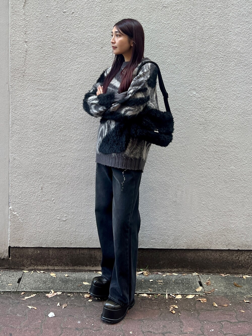 ブラック系のデニムパンツ、グレー系のニット/セーター、ブラック系のハンドバッグを着用したレディースの冬コーディネートの1枚目の写真