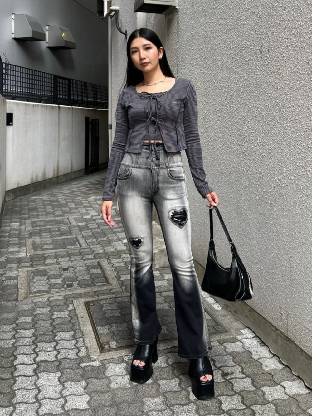 ブラック系のデニムパンツ、ブルー系のTシャツ/カットソー、ブラック系のハンドバッグを着用したレディースの夏コーディネートの1枚目の写真