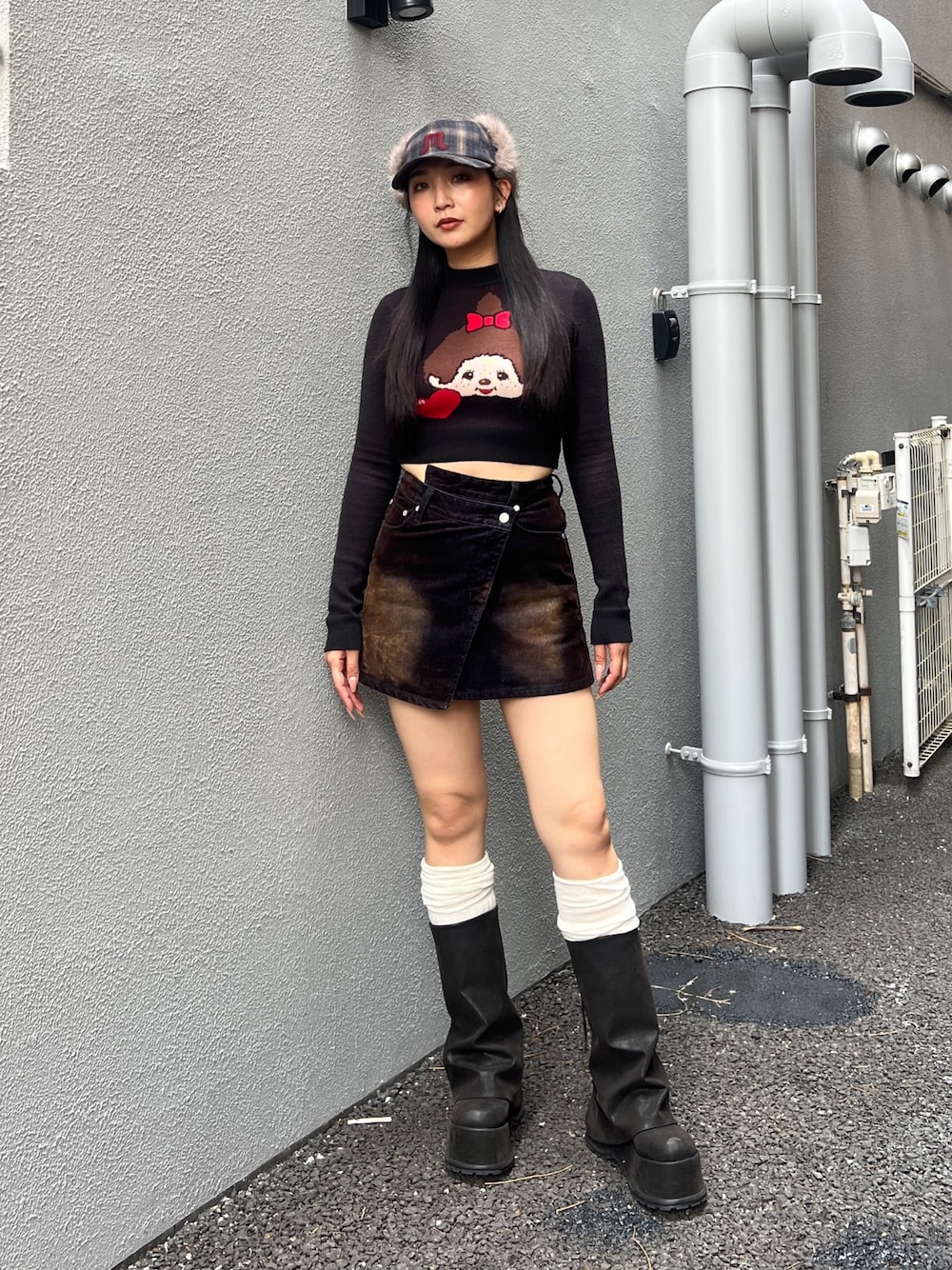 ブラック系のニット/セーター、ブラウン系のスカート、ブラック系のブーツを着用したレディースの夏コーディネートの1枚目の写真