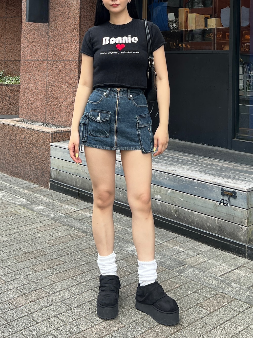 ブラック系のニット/セーター、ブルー系のスカート、ブラック系のその他シューズを着用したレディースの春コーディネートの1枚目の写真