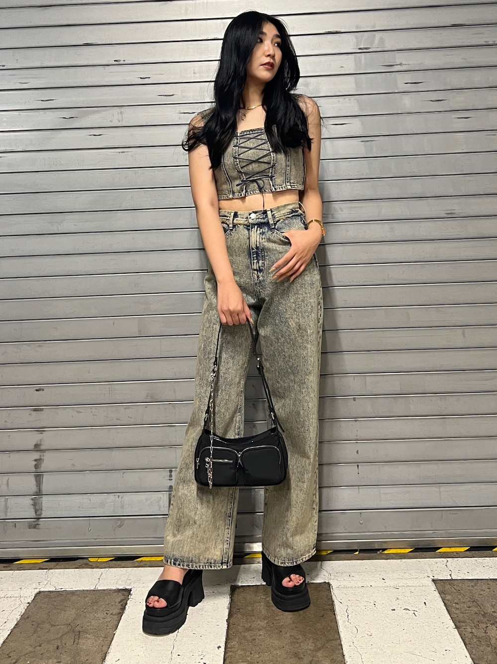 ベージュ系のデニムパンツ、ブラック系のハンドバッグ、ブラック系のサンダルを着用したレディースの夏コーディネートの1枚目の写真