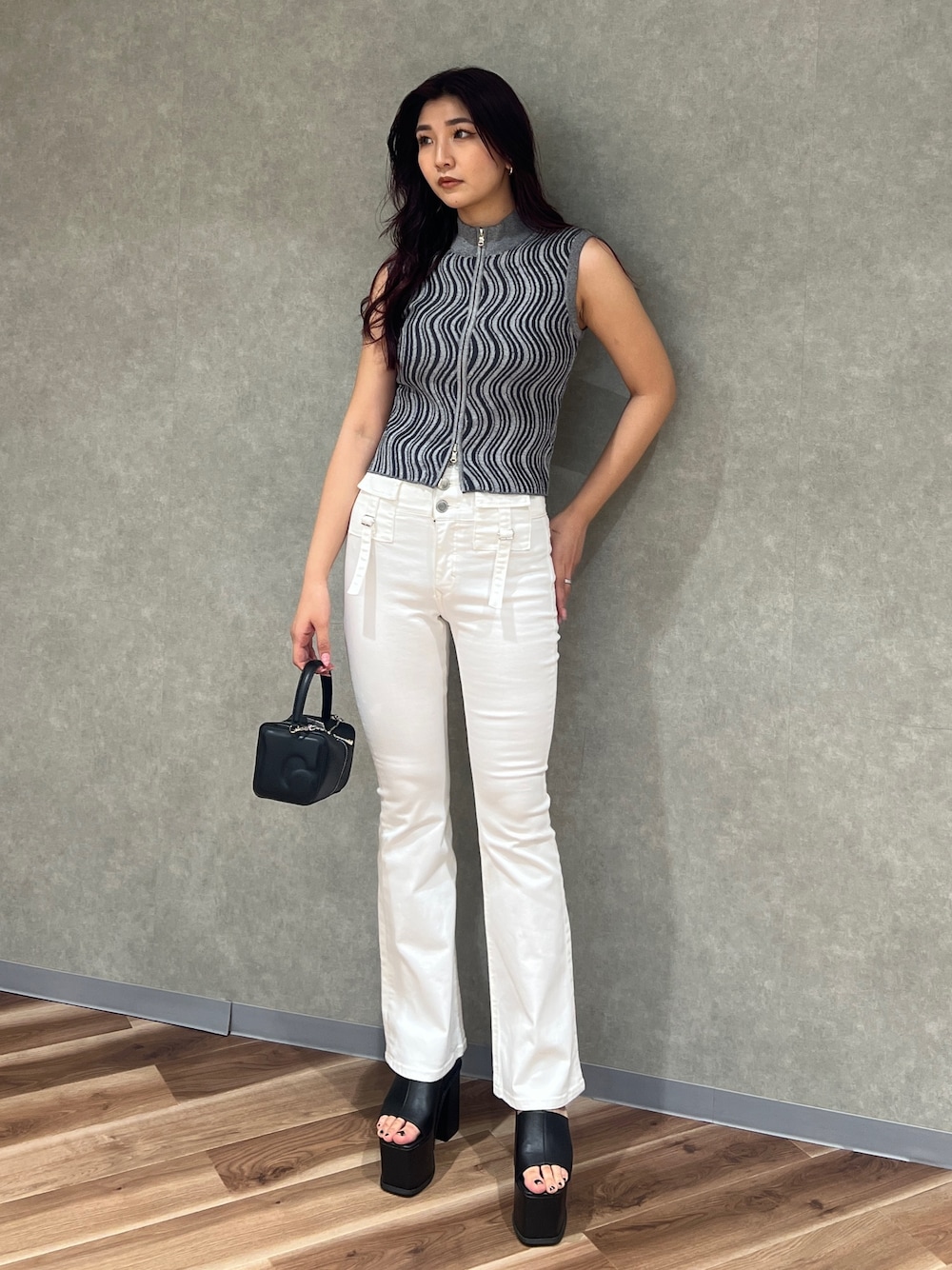 グレー系のタンクトップ、ホワイト系のデニムパンツ、ブラック系のハンドバッグを着用したレディースの夏コーディネートの1枚目の写真