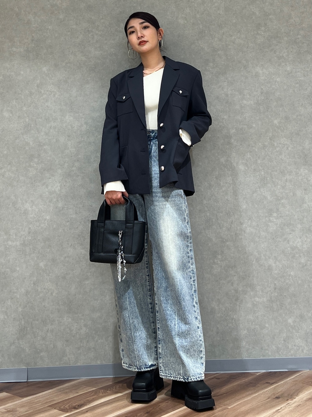 グレー系のテーラードジャケット、ブルー系のデニムパンツ、ブラック系のブーツを着用したレディースの冬コーディネートの1枚目の写真