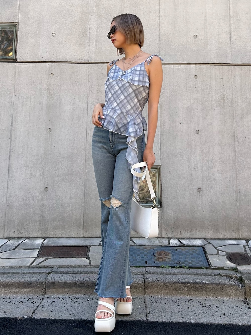 ブルー系のデニムパンツ、ブルー系のキャミソール、ホワイト系のショルダーバッグを着用したレディースの春コーディネートの1枚目の写真