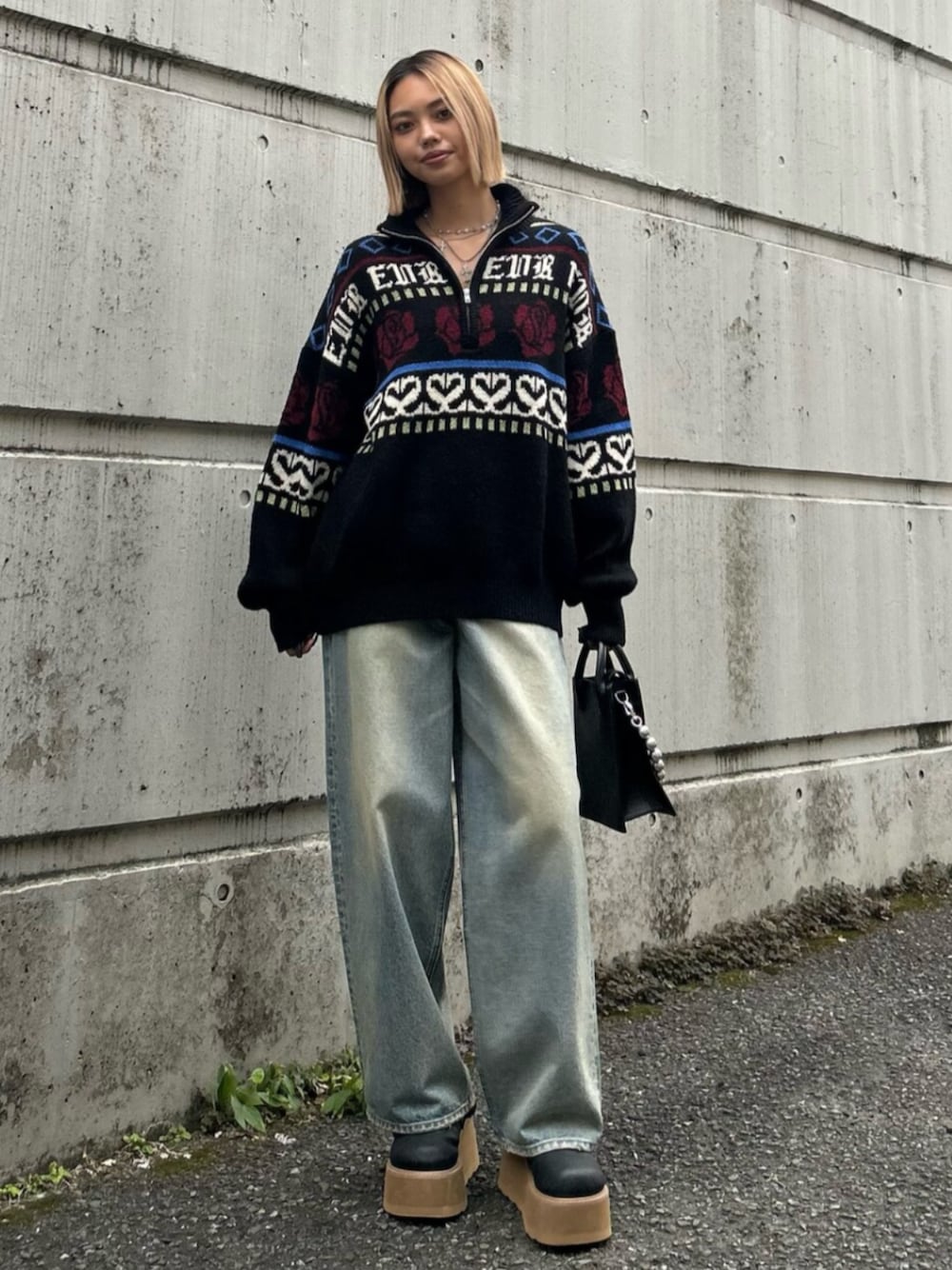 ブラック系のショルダーバッグ、ブラック系のニット/セーター、ブルー系のデニムパンツを着用したレディースの秋コーディネートの1枚目の写真