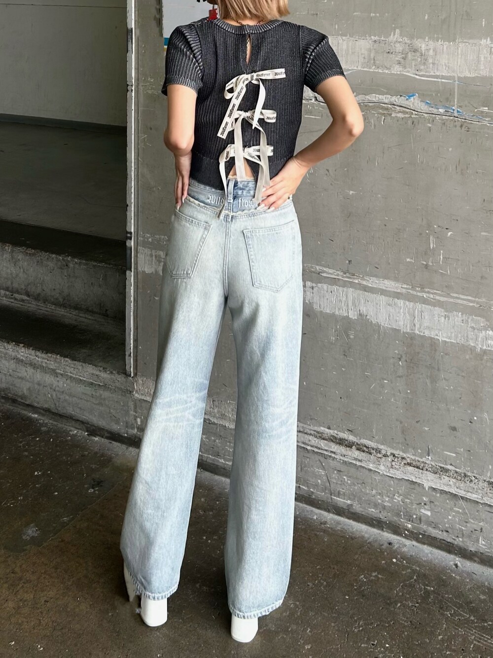 ブルー系のデニムパンツ、ブラック系のニット/セーター、ホワイト系のサンダルを着用したレディースの夏コーディネートの1枚目の写真