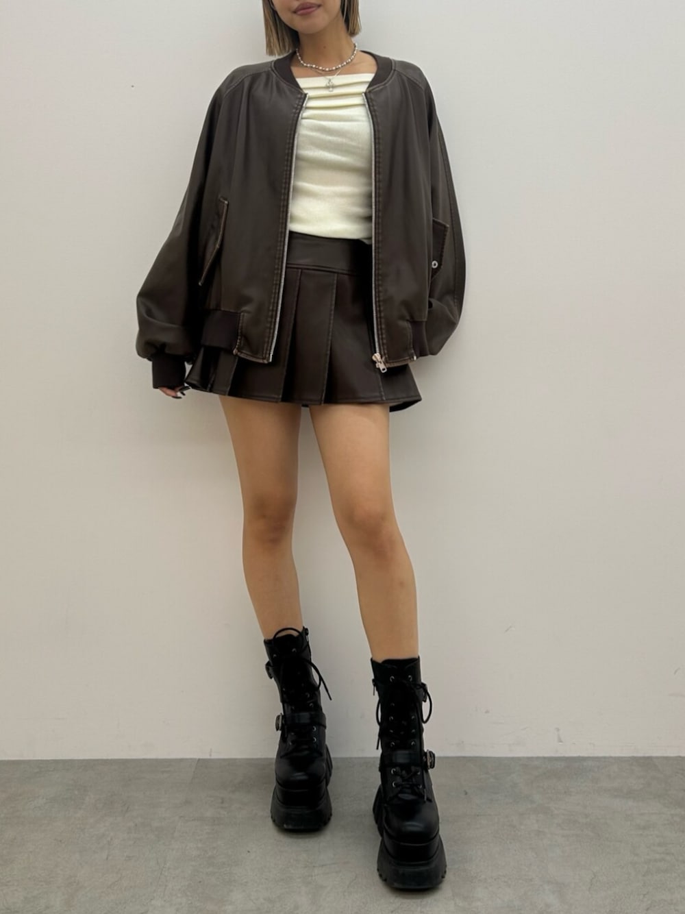 ブラック系のブーツ、ブラウン系のスカート、ブラウン系のブルゾンを着用したレディースの秋コーディネートの1枚目の写真