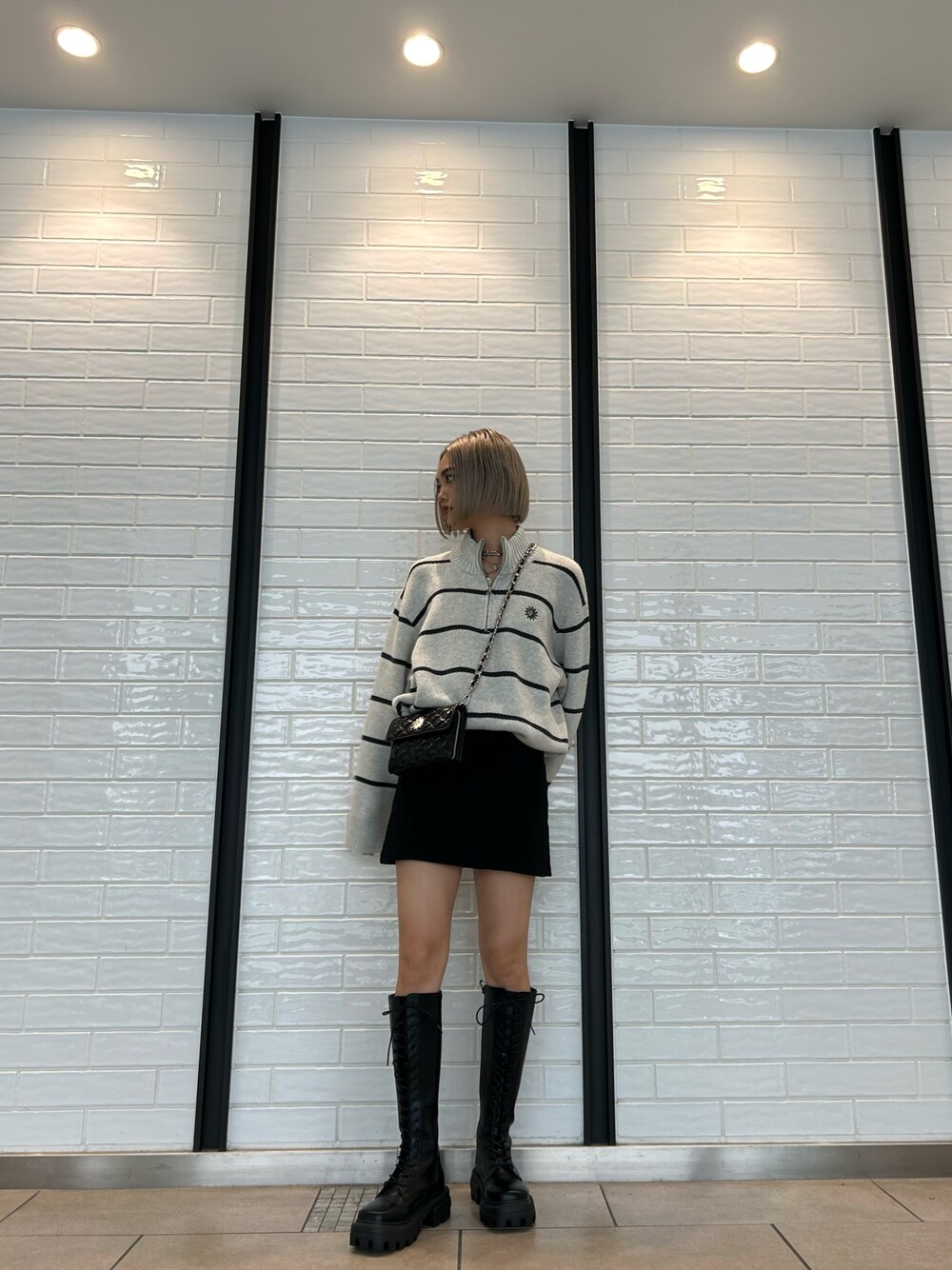 ブラック系のショルダーバッグ、ブラック系のスカート、ブラック系のブーツを着用したレディースの夏コーディネートの1枚目の写真