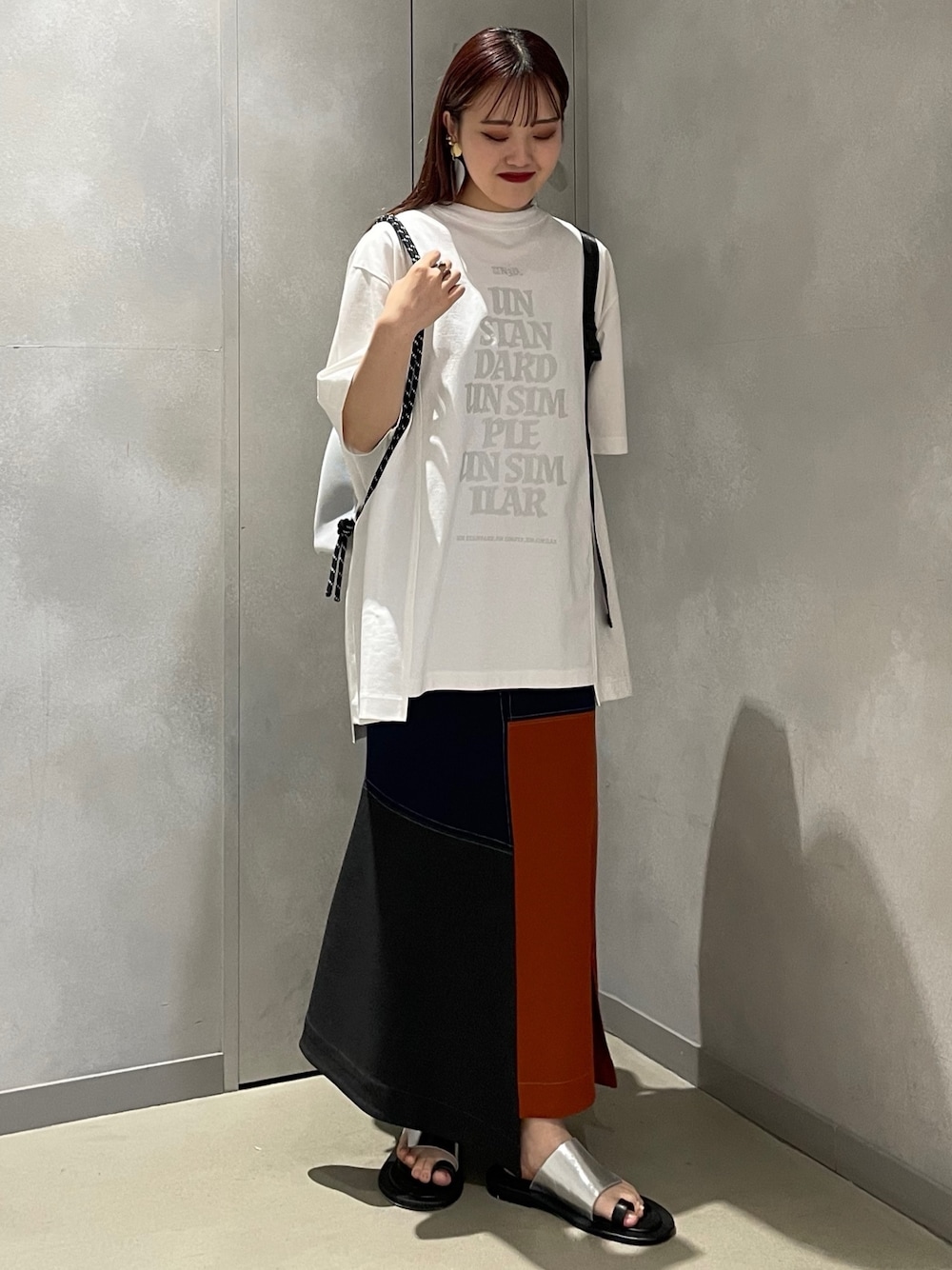 ホワイト系のTシャツ/カットソー、ホワイト系のバックパック/リュック、オレンジ系のスカートを着用したレディースの夏コーディネートの1枚目の写真