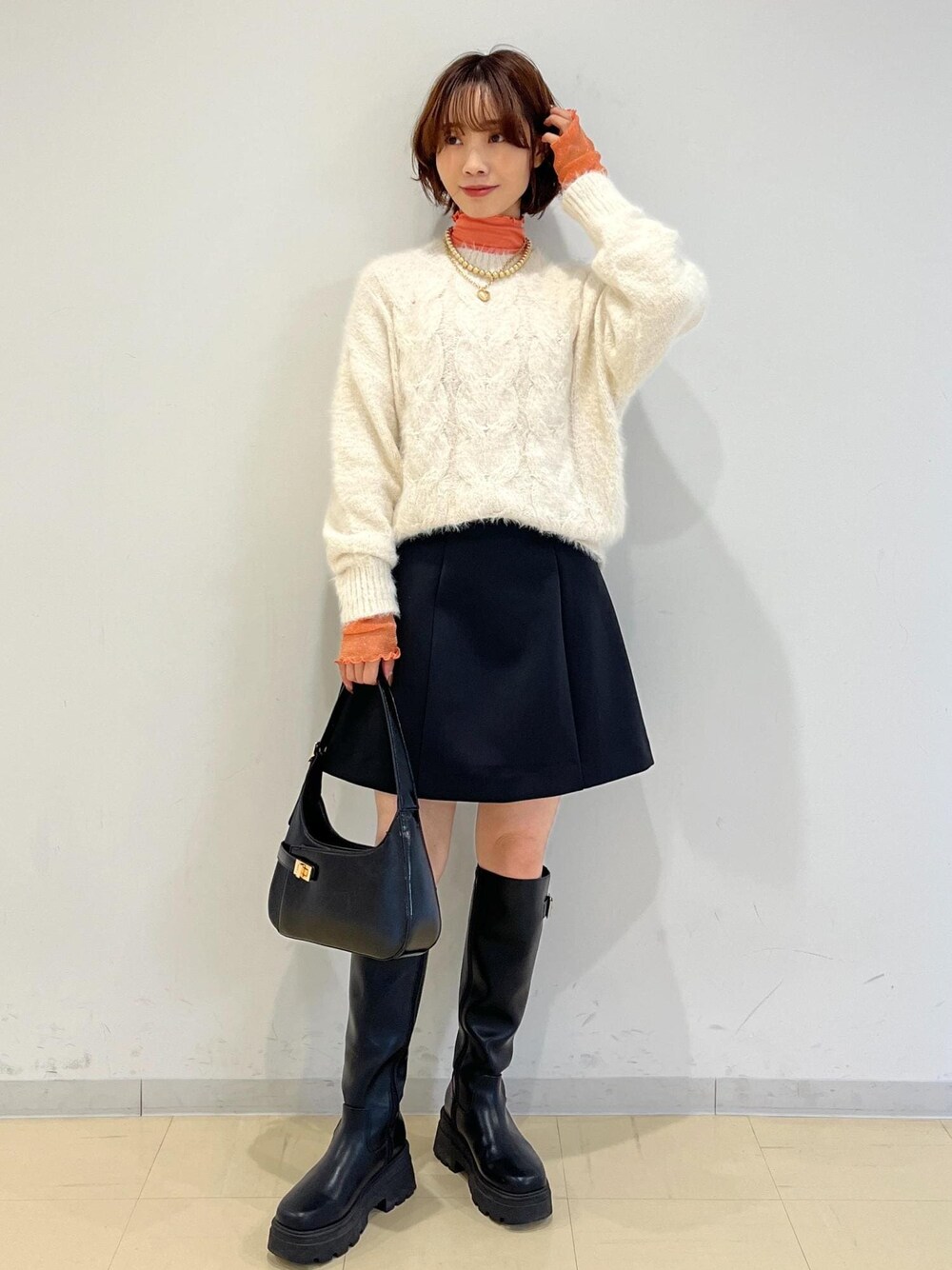 ブラック系のブーツ、ブラック系のハンドバッグ、ブラック系のスカートを着用したレディースの冬コーディネートの1枚目の写真