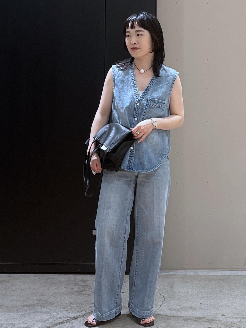 ホワイト系のキャミソール、ブラック系のサンダル、ブルー系のベストを着用したレディースの春コーディネートの1枚目の写真