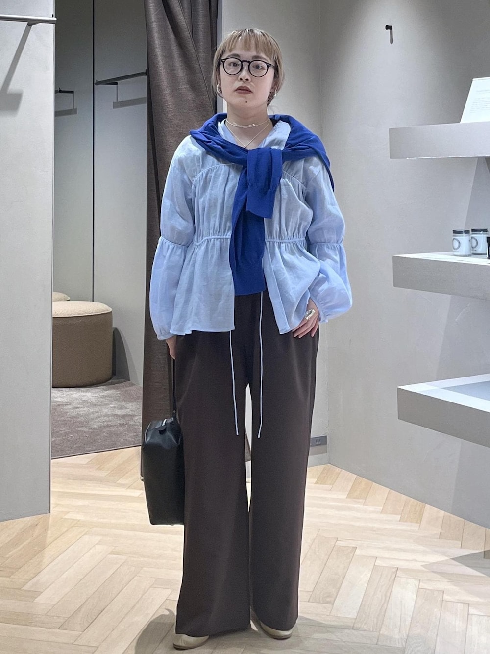 ブラック系のショルダーバッグ、ブラウン系のその他パンツ、ブルー系のニット/セーターを着用したレディースの春コーディネートの1枚目の写真