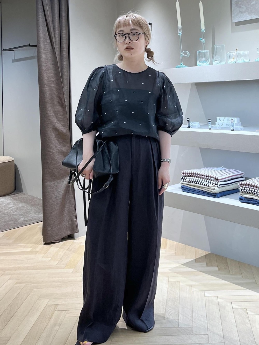 ブラック系のスラックス、ブラック系のキャミソール、ブラック系のハンドバッグを着用したレディースの春コーディネートの1枚目の写真
