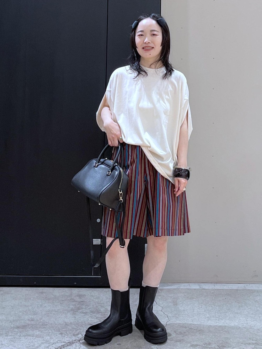 ブラック系のボストンバッグ、ブラック系のブーツ、ホワイト系のTシャツ/カットソーを着用したレディースの冬コーディネートの1枚目の写真