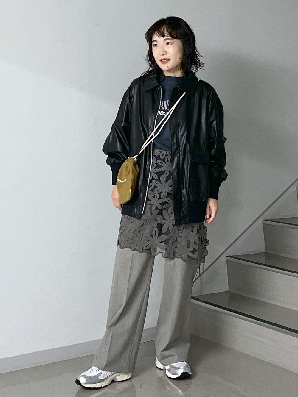 ブルー系のトートバッグ、グレー系のスラックス、ブラック系のTシャツ/カットソーを着用したレディースの秋コーディネートの1枚目の写真