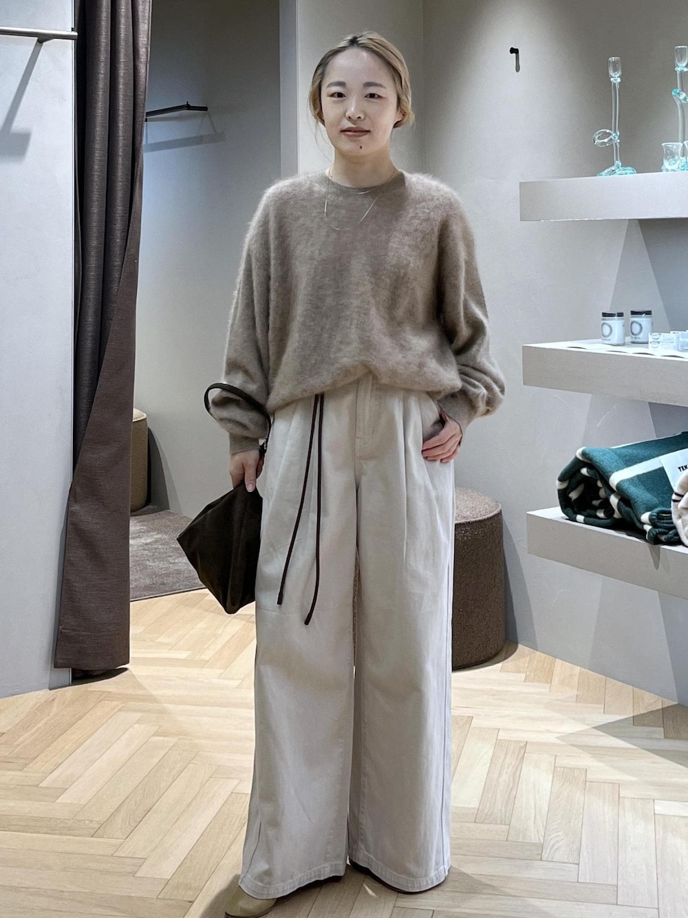 ブラウン系のショルダーバッグ、ベージュ系のニット/セーター、ホワイト系のデニムパンツを着用したレディースの冬コーディネートの1枚目の写真