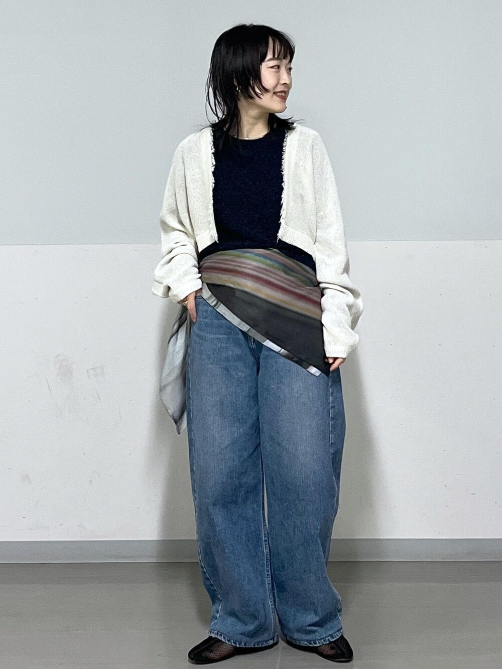 ブラック系のパンプス、ブルー系のデニムパンツ、ホワイト系のカーディガン/ボレロを着用したレディースの冬コーディネートの1枚目の写真