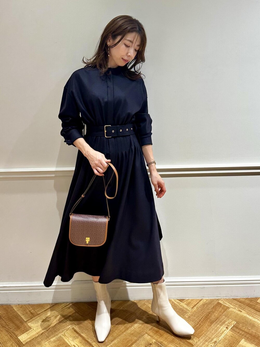 ブラウン系のショルダーバッグ、ホワイト系のブーツ、ブルー系のワンピースを着用したレディースの冬コーディネートの1枚目の写真