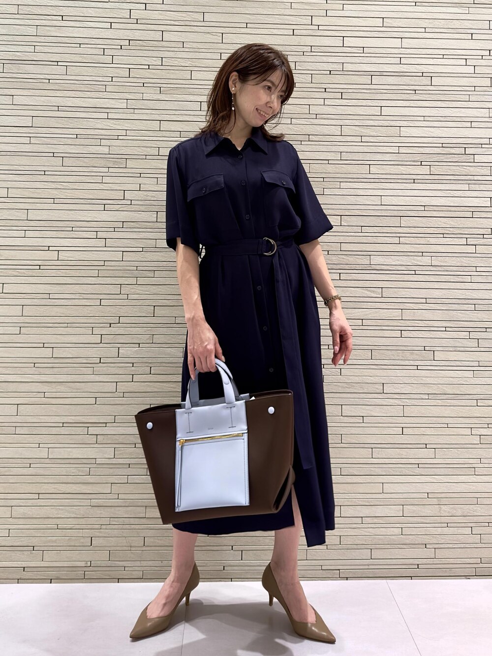 ブラウン系のハンドバッグ、ベージュ系のパンプス、ブルー系のワンピースを着用したレディースの夏コーディネートの1枚目の写真