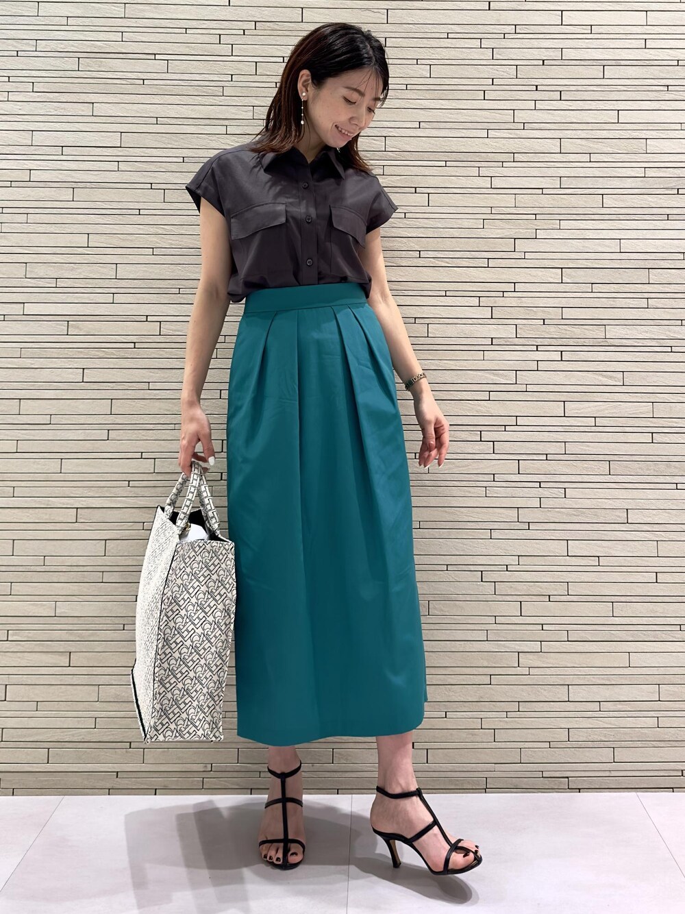 ブラック系のトートバッグ、ブラウン系のシャツ/ブラウス、グリーン系のスカートを着用したレディースの夏コーディネートの1枚目の写真