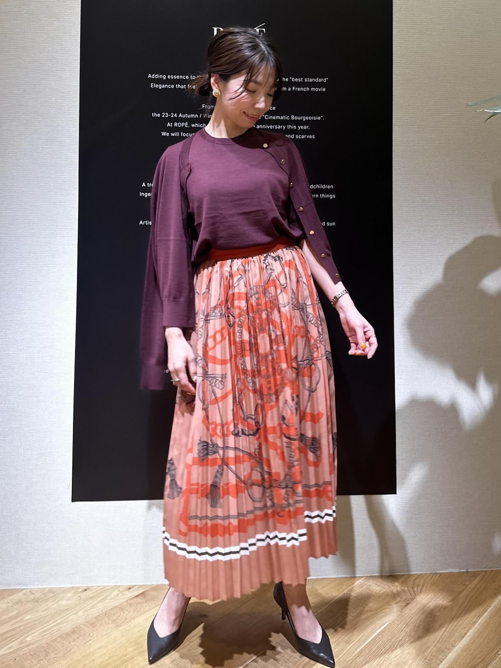 ベージュ系のパンプス、レッド系のニット/セーター、レッド系のカーディガン/ボレロを着用したレディースの夏コーディネートの1枚目の写真