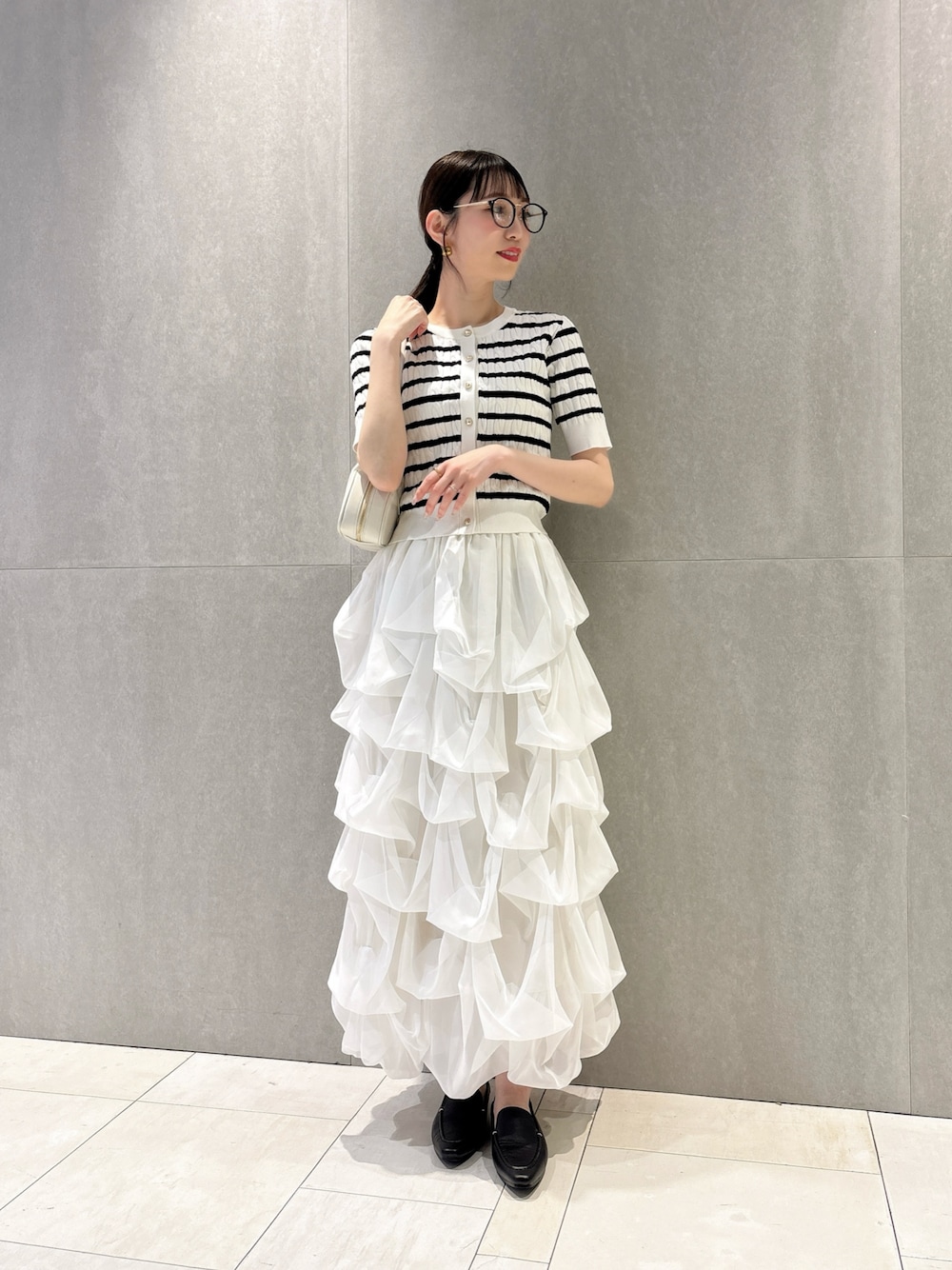 ホワイト系のカーディガン/ボレロ、ホワイト系のスカート、ホワイト系のショルダーバッグを着用したレディースの夏コーディネートの1枚目の写真