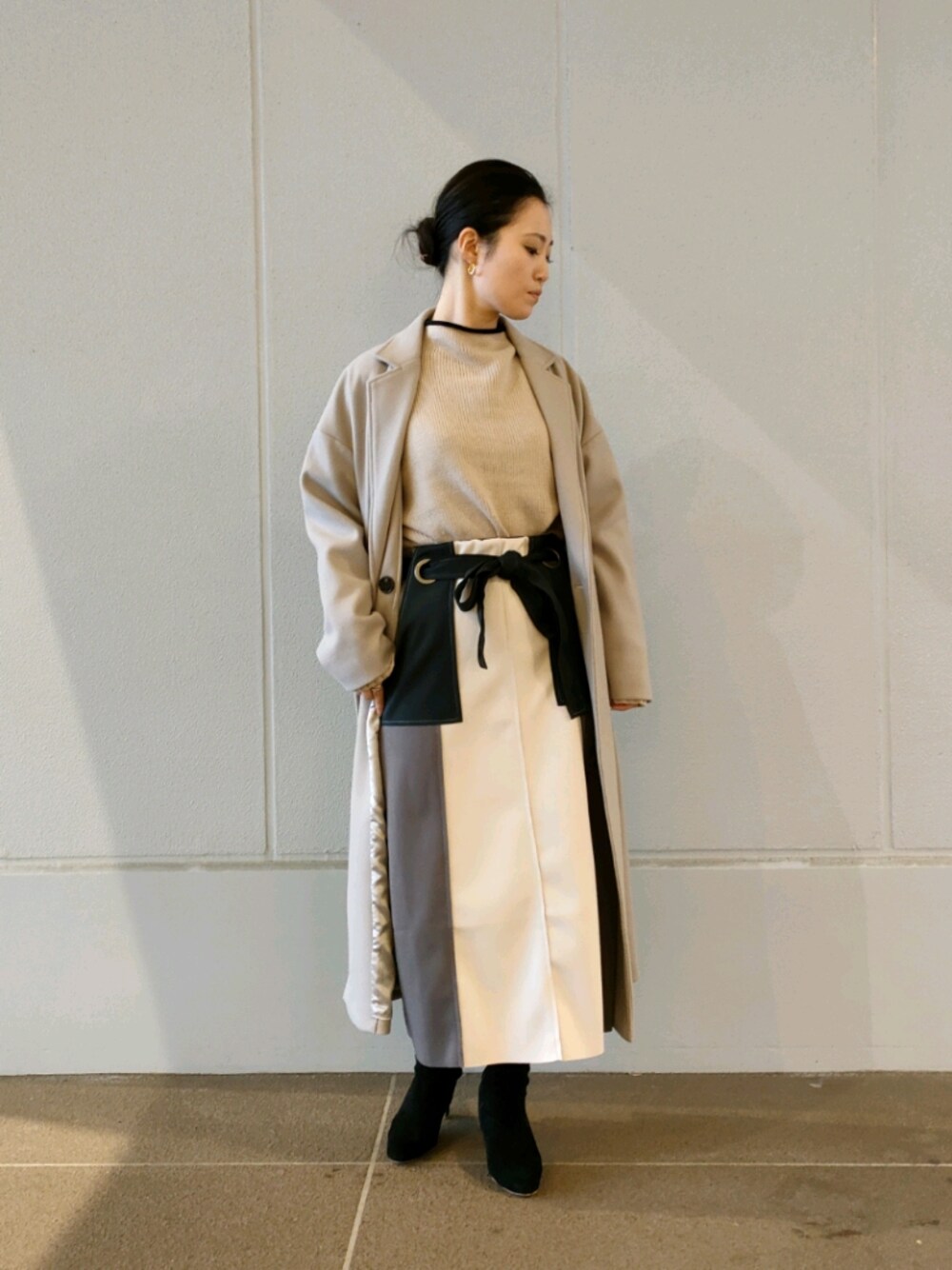 ベージュ系のニット/セーター、グリーン系のスカート、ベージュ系のその他アウターを着用したレディースの秋コーディネートの1枚目の写真