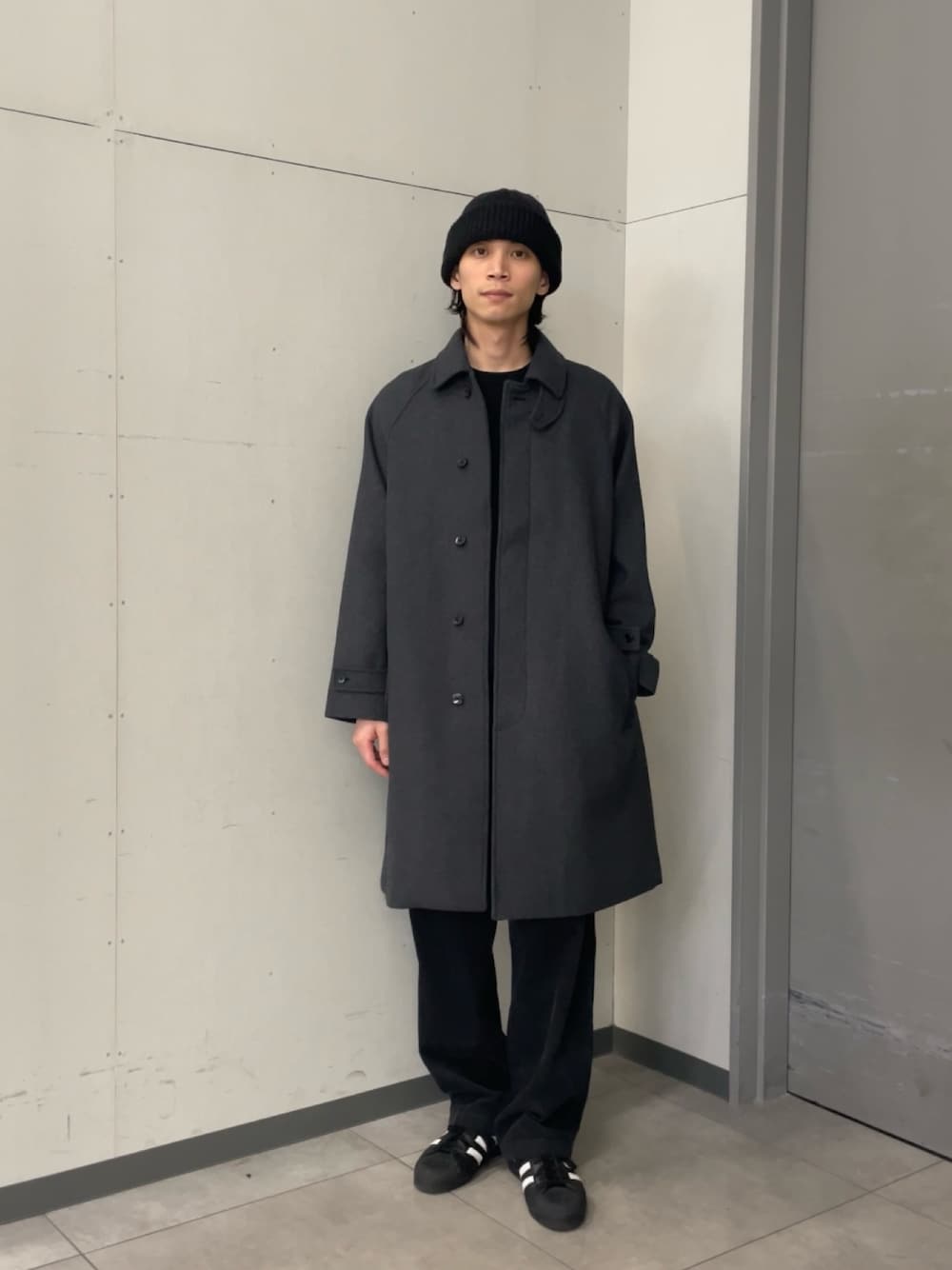 グレー系のステンカラーコート、ブラック系のニット/セーター、グレー系のその他パンツを着用したメンズの秋コーディネートの1枚目の写真