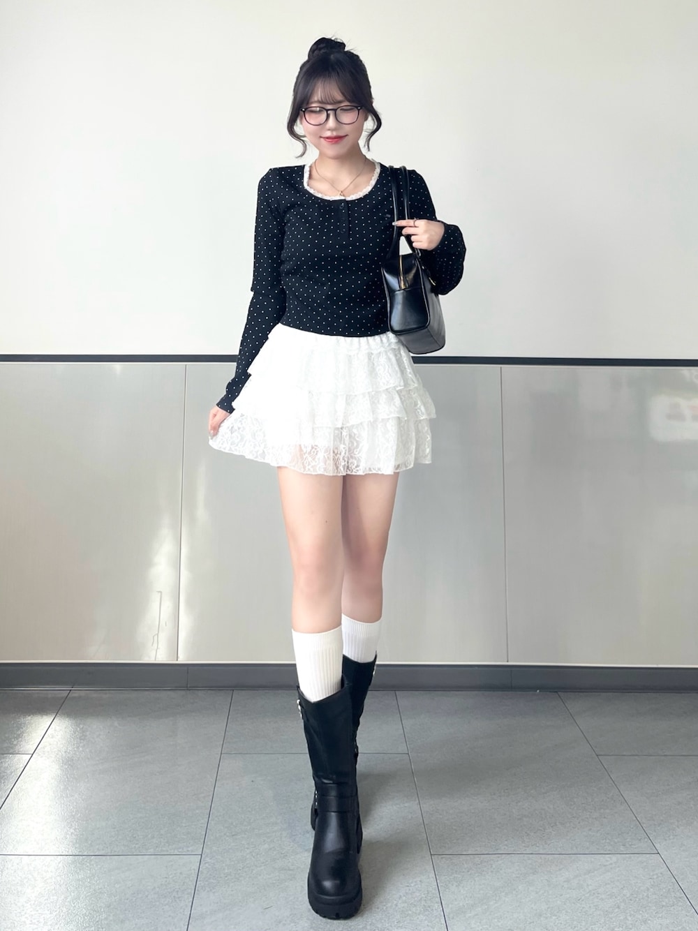 ブラック系のTシャツ/カットソー、ホワイト系のスカート、ブラック系のブーツを着用したレディースの秋コーディネートの1枚目の写真