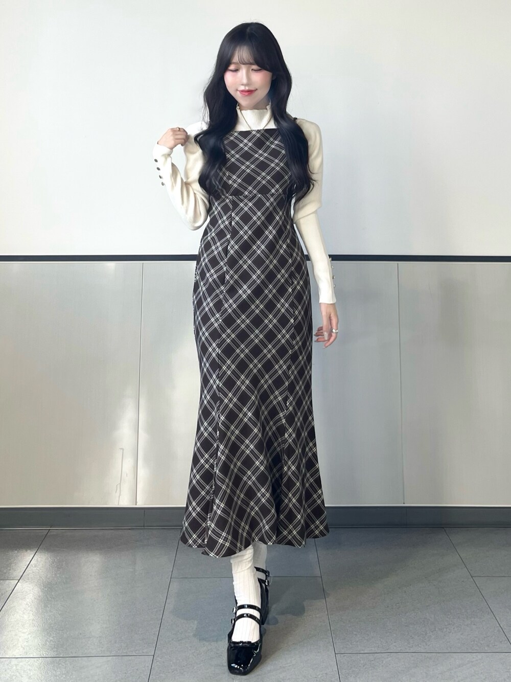 ホワイト系のニット/セーター、ブラウン系のワンピース、ブラック系のパンプスを着用したレディースの秋コーディネートの1枚目の写真