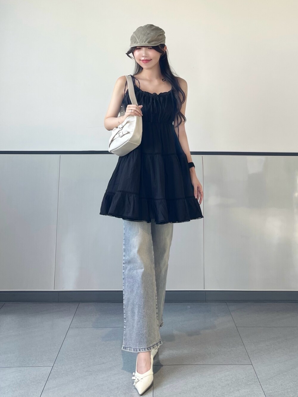 ブラック系のワンピース、ブルー系のデニムパンツ、ホワイト系のパンプスを着用したレディースの夏コーディネートの1枚目の写真