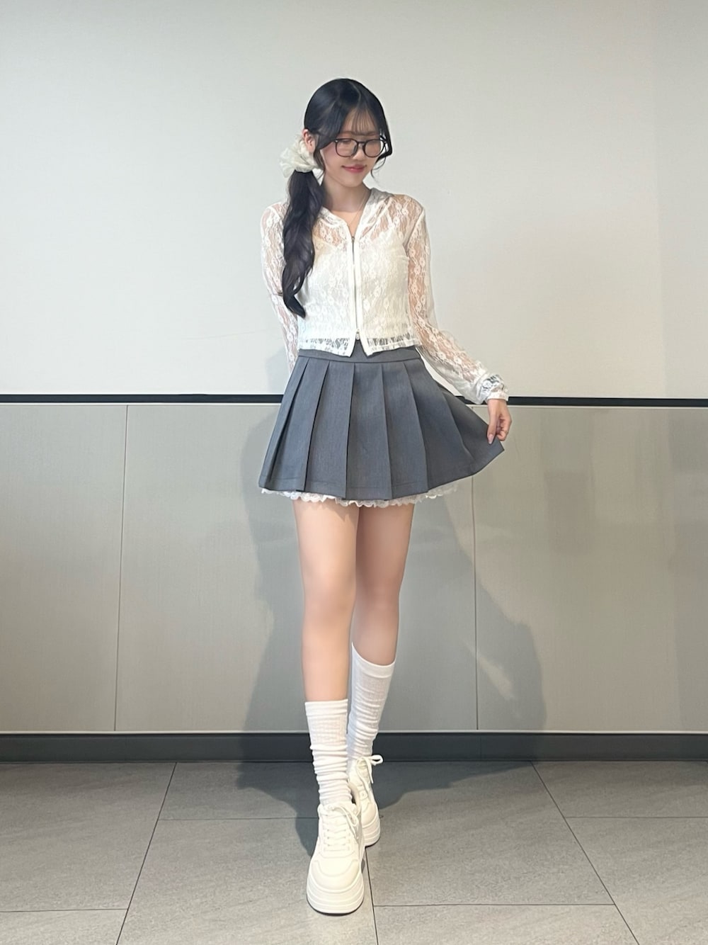 ホワイト系のパーカー、グレー系のスカート、ホワイト系のスニーカーを着用したレディースの夏コーディネートの1枚目の写真