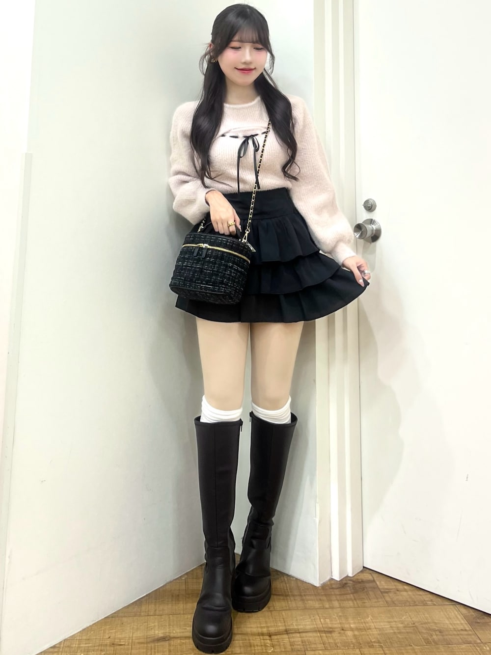 ピンク系のニット/セーター、ブラック系のスカート、ブラック系のショルダーバッグを着用したレディースの冬コーディネートの1枚目の写真