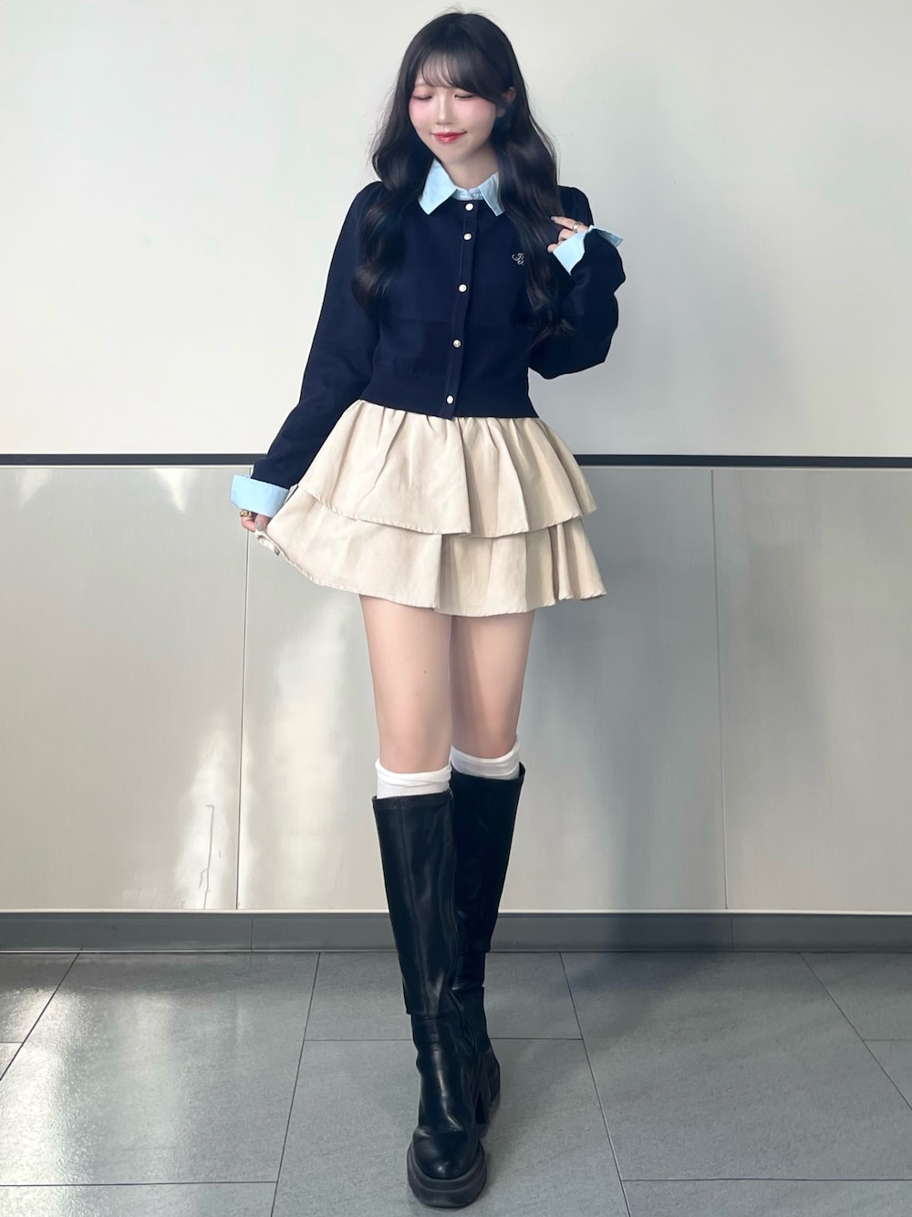 ブルー系のニット/セーター、ホワイト系のスカート、ブラック系のブーツを着用したレディースの秋コーディネートの1枚目の写真