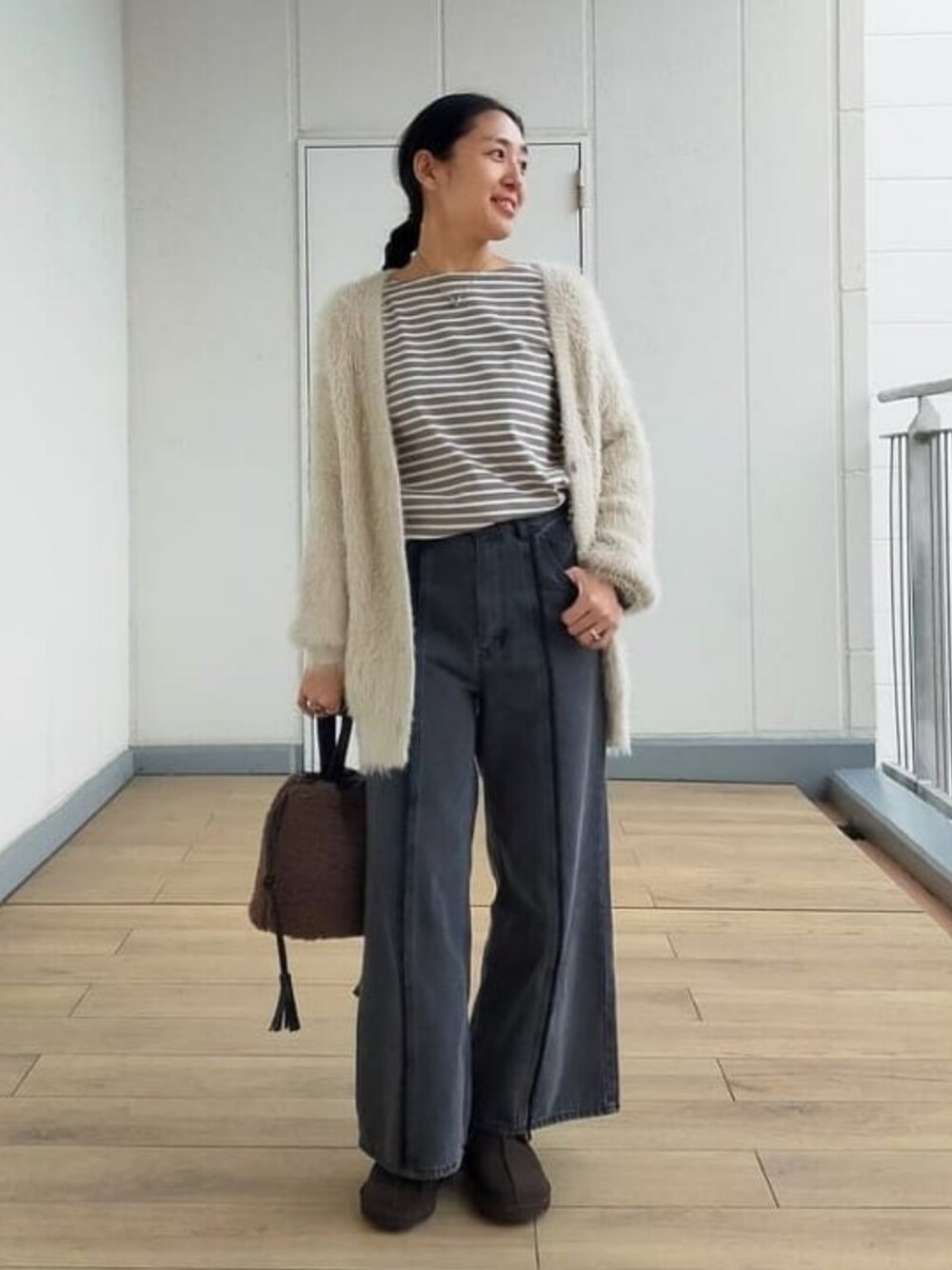 ホワイト系のカーディガン/ボレロ、グリーン系のTシャツ/カットソー、ブラック系のデニムパンツを着用したレディースの冬コーディネートの1枚目の写真
