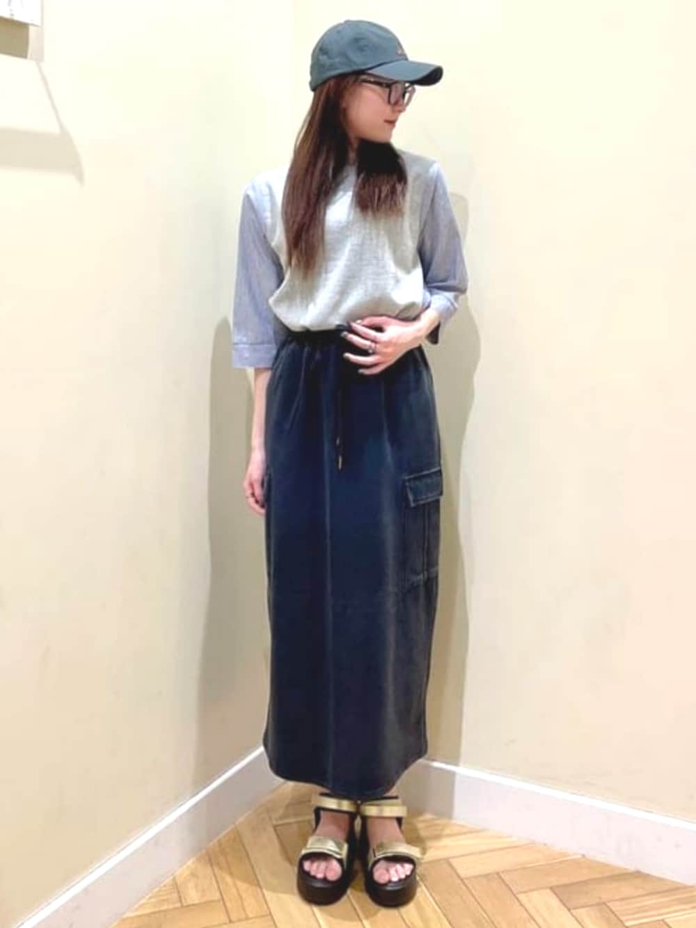 グレー系のTシャツ/カットソー、ブラック系のスカート、ゴールド系のサンダルを着用したレディースの春コーディネートの1枚目の写真