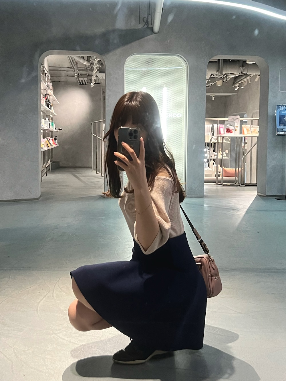 ホワイト系のニット/セーター、ブルー系のスカート、ピンク系のショルダーバッグを着用したレディースの秋コーディネートの1枚目の写真